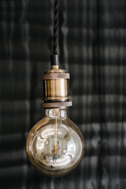 Photo decorative style antique edison light bulbs on the dark gray wall background. loft interior details, decor in restaurant on wedding.