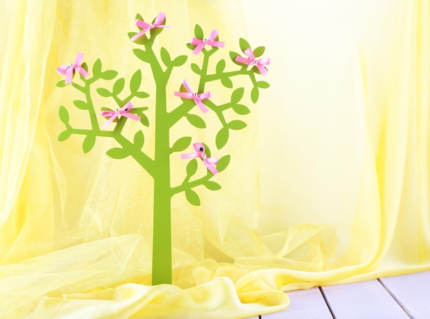 Decorative tree with  bows, on wooden table on color fabric background