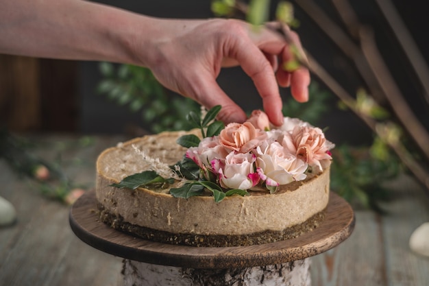 Decorator's hand decorating the mousse cake with tenderness pink flowers