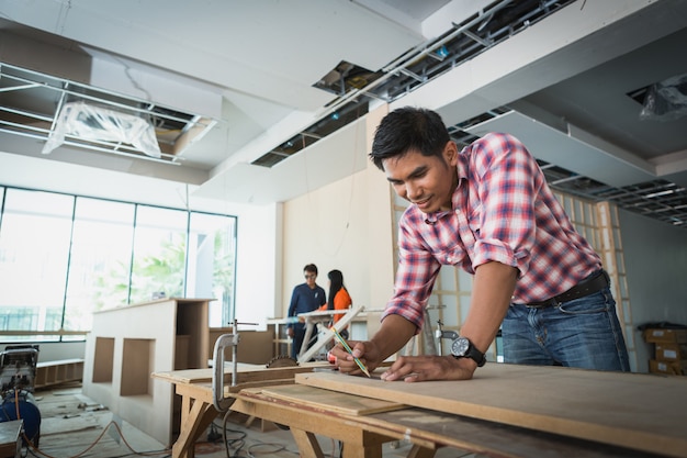 Decorator working on design and inspect of plywood at construction site; decorator checking material for interior