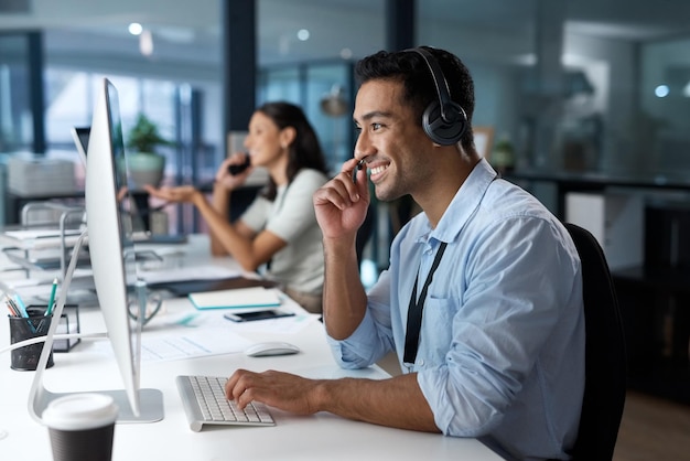 Dedicated service creates dedicated customers Shot of a young man using a headset and computer in a modern office