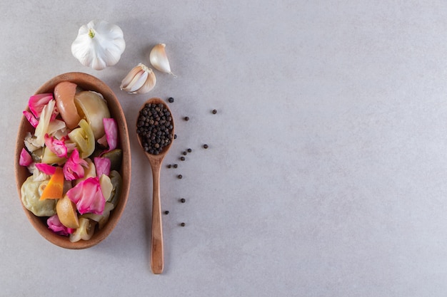 Deep bowl with various pickled vegetables stone table.