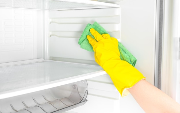 Deep Cleaning service House cleaning Washing fridge Woman hand in yellow rubber protective glove cleaning white open empty refrigerator with green rag copy space