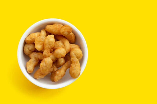 Deep-fried dough stick, chinese bread stick in white bowl on yellow surface