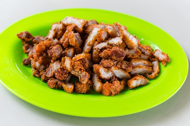 Deep fried golden color crispy pork belly plating on green plate.