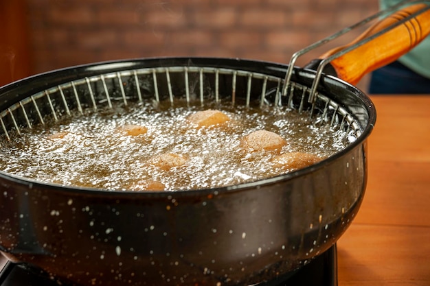 Deep frying brazilian croquettes stuffed with chiken in boiling soybean oil Coxinha de frango