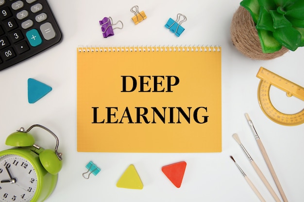 Deep learning is written in a notebook on an office table with office supplies