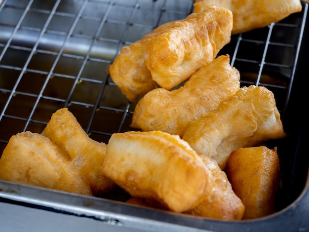 Deepfried dough sticks or Patongko in Thai Asian famous street food in Thailand Chinese doughnuts A traditional yellow crispy snack made from flour and cooked in pan with hot oil