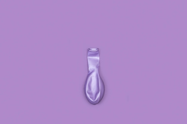 A deflated purple balloon on a purple background with copy space