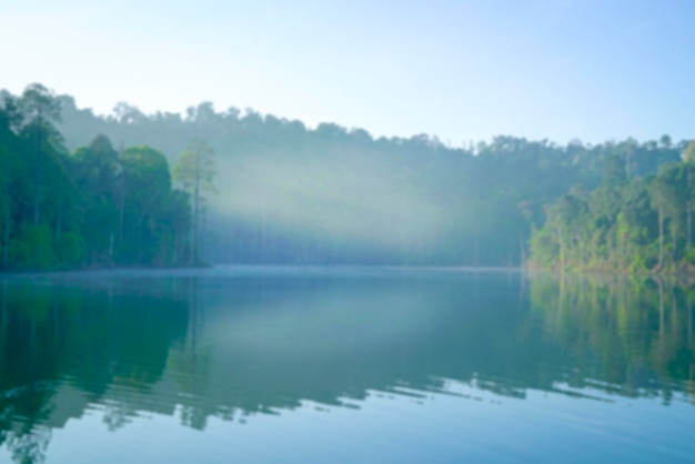 Defocused bokeh background of forest and lake with morning fog