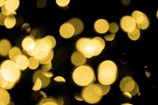 Defocused bokeh christmas large gold lights on black background Blur abstract gold glitter texture