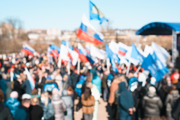 Defocused crowd of people with flags outdoors on sunny day National holiday demonstration parade celebration concept Blurred human background