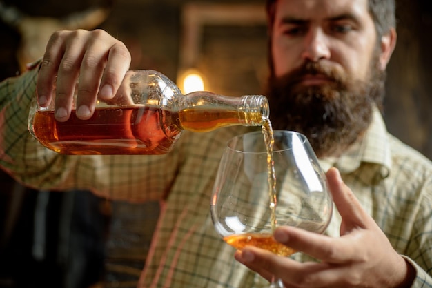 Degustation tasting man with beard holds glass of brandy