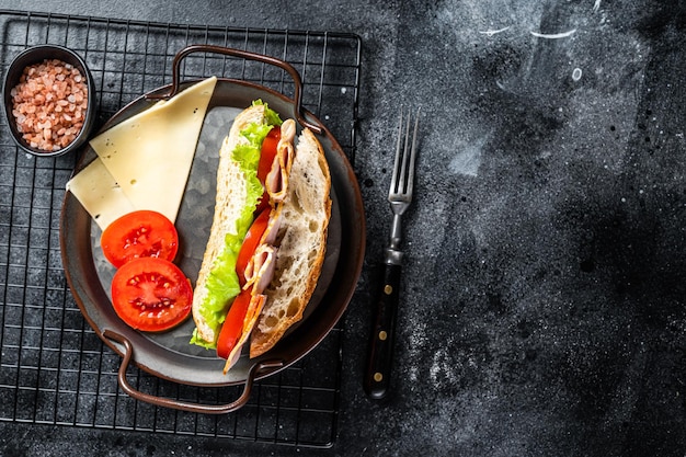 Deli meat sandwich with turkey ham cheese tomato and Lettuce Black background Top view Copy space