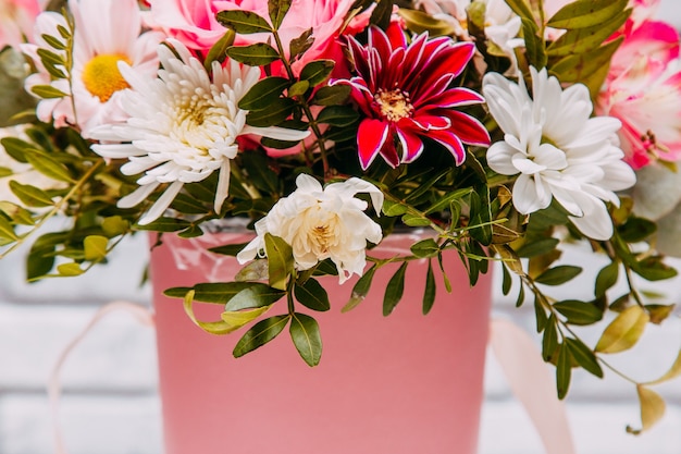 Delicate bouquet of different flowers in pink packaging. 