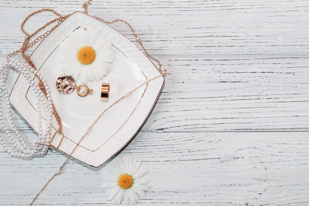 Delicate daisies close-up with gold jewelry. Chains, pendants, rings on a stand.