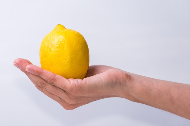 Delicate hand with a lemon yellow fruits and vegetables healthy living lifestyle