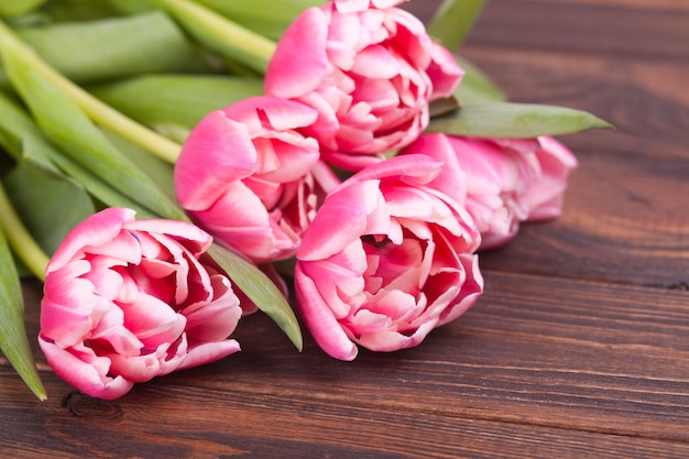 Delicate pink tulips on a brown wooden background. Close-up. Flowers composition. Floral spring background. Valentine's Day, Easter, Mother's Day.