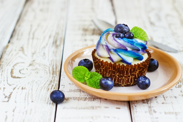 Delicate vanilla cupcakes with cream and berries on a white wooden