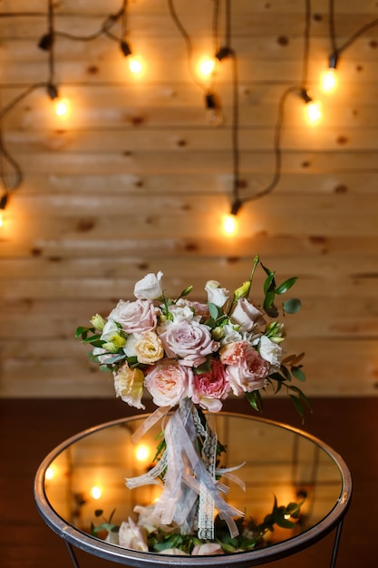 Delicate and very beautiful wedding bouquet of roses greenery eustoma standing on mirror table