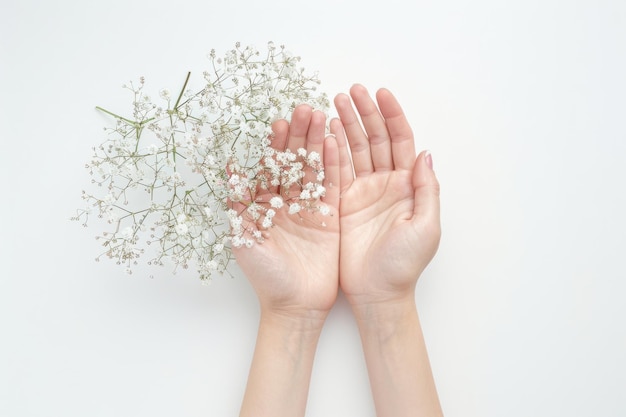 Delicate white flowers cradled in gentle hands against a soft neutral background