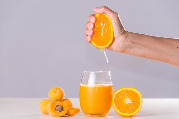 Delicate woman squeezing orange for natural juice orange and apricot diet light