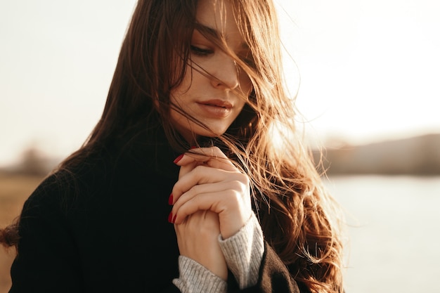 Delicate woman standing near lake in autumn