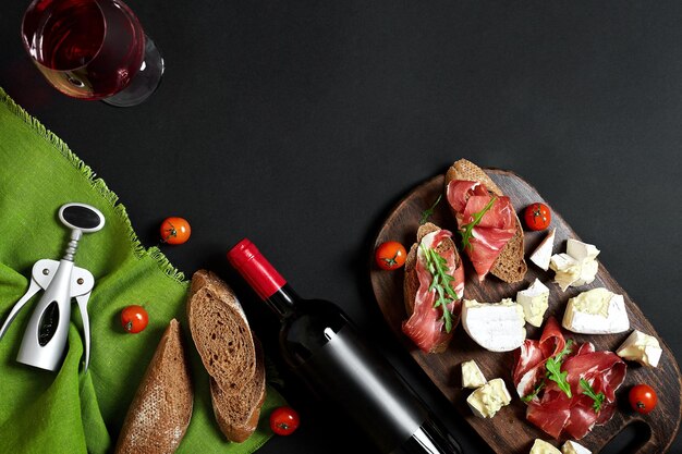 Delicious appetizer to wine ham cheese baguette slices tomatoes served on a wooden board and glass w