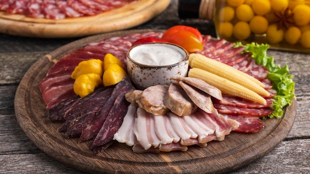 Delicious appetizer with different sausages and pickled vegetables on wooden board