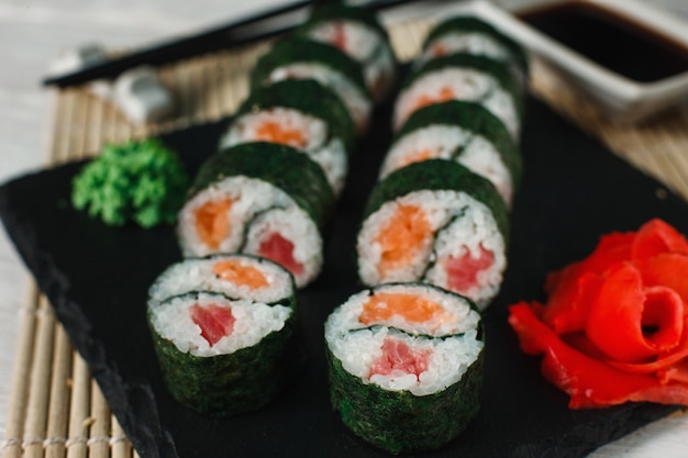 Delicious and appetizing set of sushi served on black slate on Japanese restaurant, closeup. Fresh yin yang maki, Asian cuisine, healthy food art.