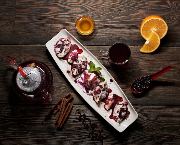 Delicious Asian dessert in long white plate with teapot orange berries and spices Asian menu Dark wooden background