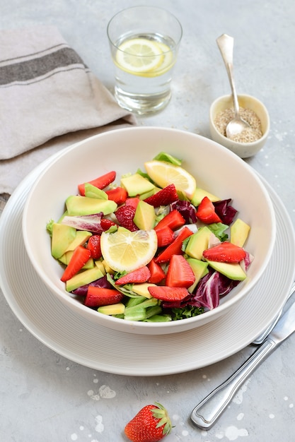 delicious avocado salad with  strawberries on a white plate. keto food recipe. healthy lunch