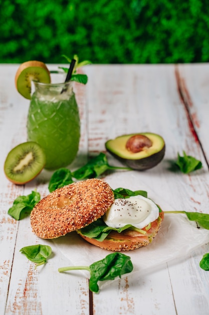 Delicious bagel with sesame and chia bread, inside it contains salmon, fried egg and basil.