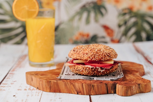 Delicious bagel with sesame and chia bread, inside it contains tomato, ham and chicken in strips.