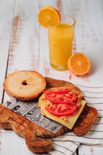 Delicious bagel with sesame and chia bread, inside it contains tomato, ham and chicken in strips.