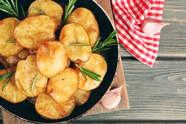 Delicious baked potato with rosemary in frying pan on table close up