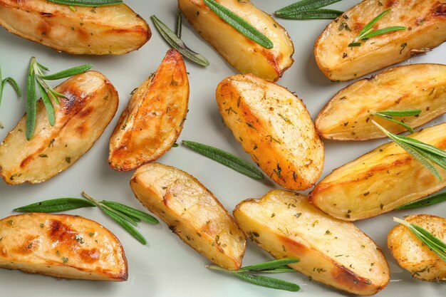 Delicious baked potatoes with rosemary on light background closeup