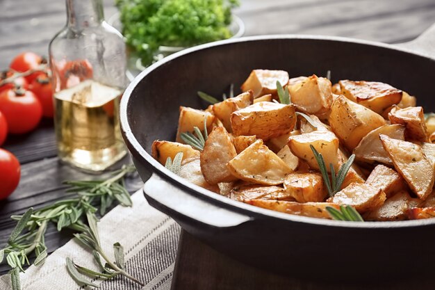 Delicious baked potatoes with rosemary in pan on table