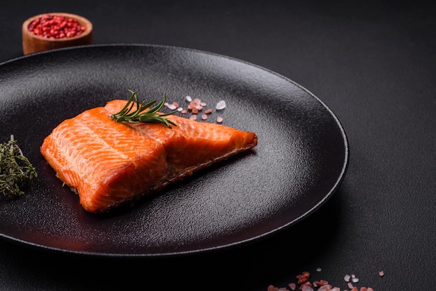 Delicious baked salmon red fish steak with spices and herbs on a dark concrete background