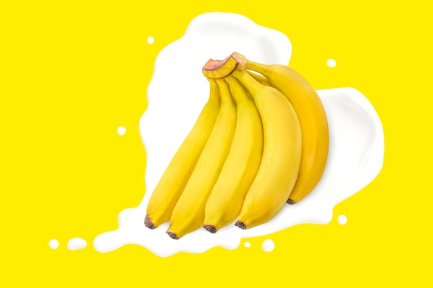 Delicious Banana bunch with heart shape milk splash on yellow background