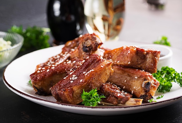 Delicious barbecued spare ribs on plate on dark background Tasty bbq meat