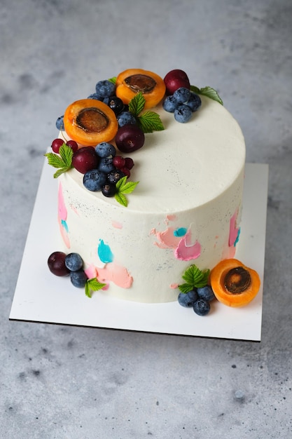 Delicious and beautiful handmade cake. Confectionery for the holiday. Dessert is decorated with fresh blueberries, apricots, cherries and red currants.