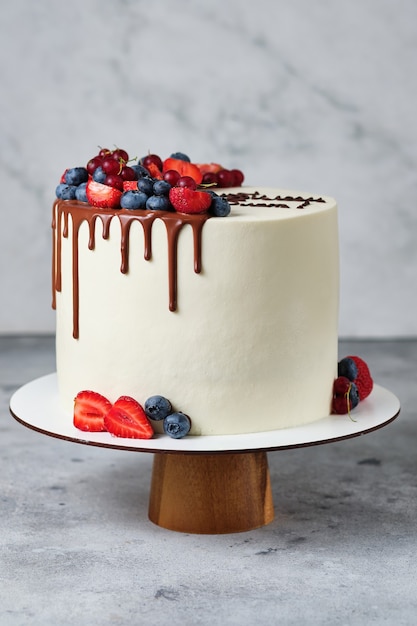 Delicious and beautiful handmade cake. Confectionery for the holiday. The dessert is decorated with fresh strawberries, blueberries and red currants.