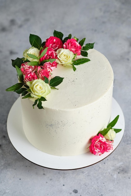 Delicious and beautiful handmade cake. Wedding confectionery. The white cake is decorated with natural rose flowers.