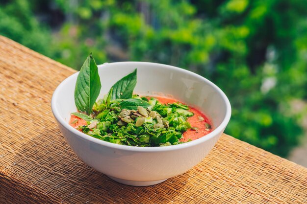 Delicious beautiful raw vegan salad from green leaves mix vegetables in white plate Cooking recipe Blended tomato carrot cauliflower cut parsley cilantro dill greenery cucumber basil pumpkin seeds