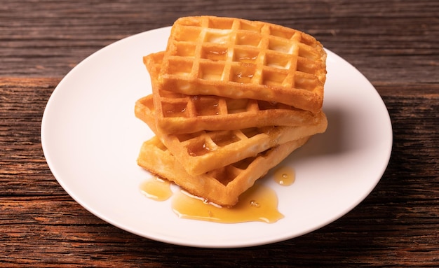 Delicious Belgian waffles with honey served on white plate and wooden background rustic conceptxA