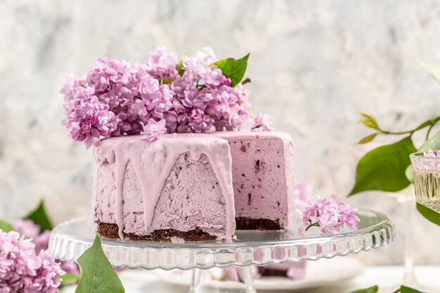 Delicious berry mousse cake with prosecco champagne wine bouquet of purple blooming lilacs French cuisine postcard background