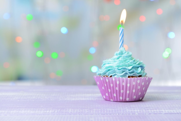 Delicious birthday cupcake on table on light background