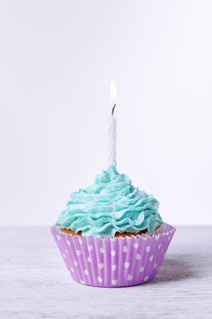 Delicious birthday cupcake on table on white background