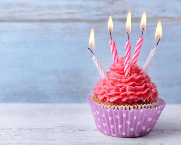 Delicious birthday cupcake on table on wooden background